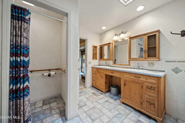 a spacious bathroom with a double vanity sink a mirror and a shower