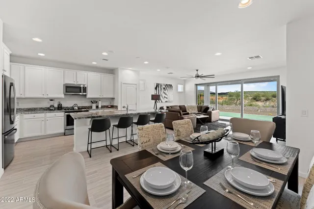a open dining room with furniture a large window and stainless steel appliances