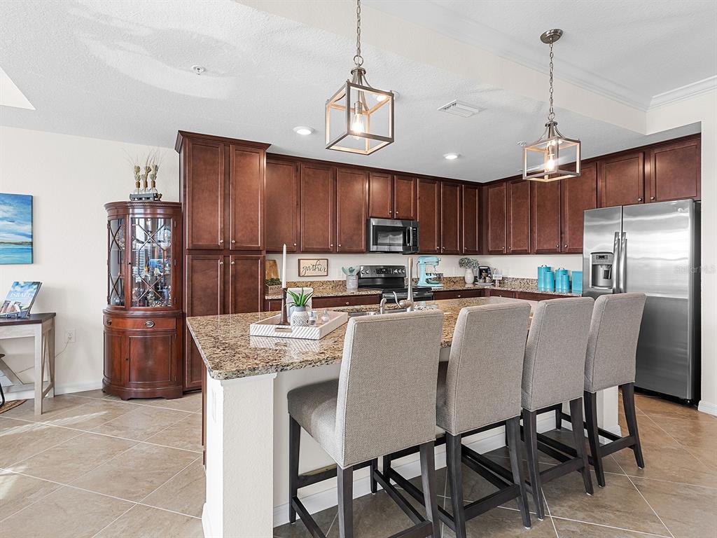 17108 Vardon Terrace, Unit 203 Lakewood Ranch, FL 34211 - Photo 13 of 50 a kitchen with stainless steel appliances granite countertop a refrigerator a stove a sink dishwasher a dining table and chairs with wooden cabinets