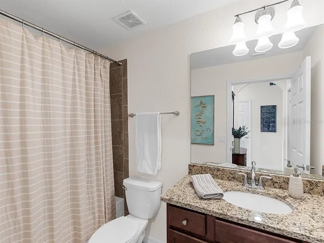 a bathroom with a granite countertop sink toilet and mirror
