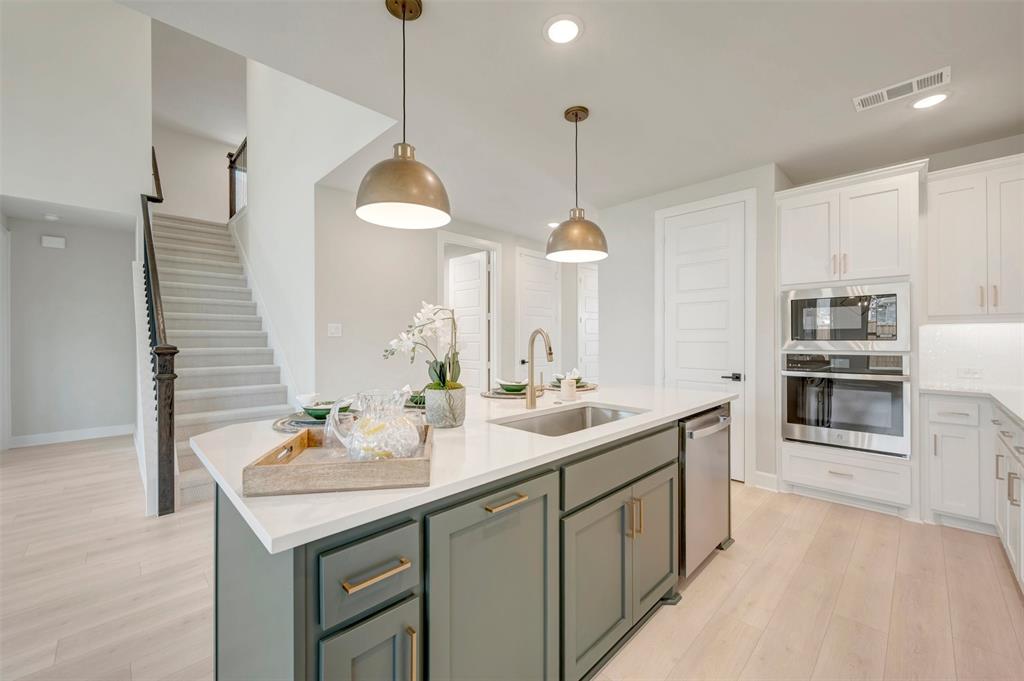 4308 Palomino Road Aubrey, TX 76227 - Photo 17 of 40 a kitchen with stainless steel appliances granite countertop a sink and a wooden floor