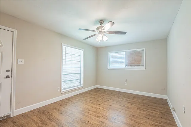 a view of an empty room with a window and wooden floor