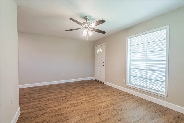 a view of an empty room with a window and wooden floor