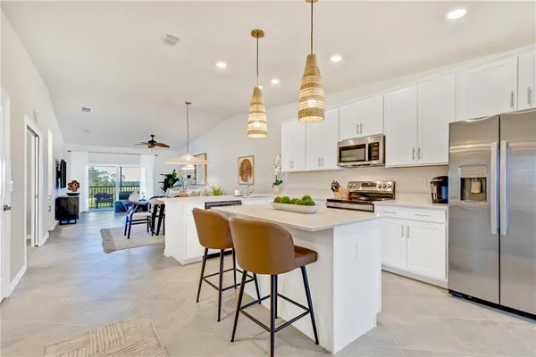 a kitchen with stainless steel appliances granite countertop a refrigerator a sink dishwasher a stove a kitchen island with a dining table and chairs
