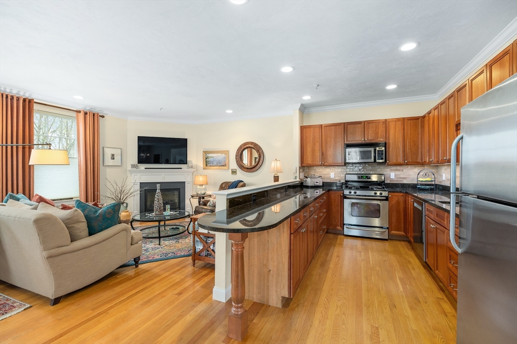 6 Essex Road, Unit 8 Ipswich, MA 01938 - Photo 6 of 35 a kitchen with granite countertop wooden floors a stove a sink and a microwave