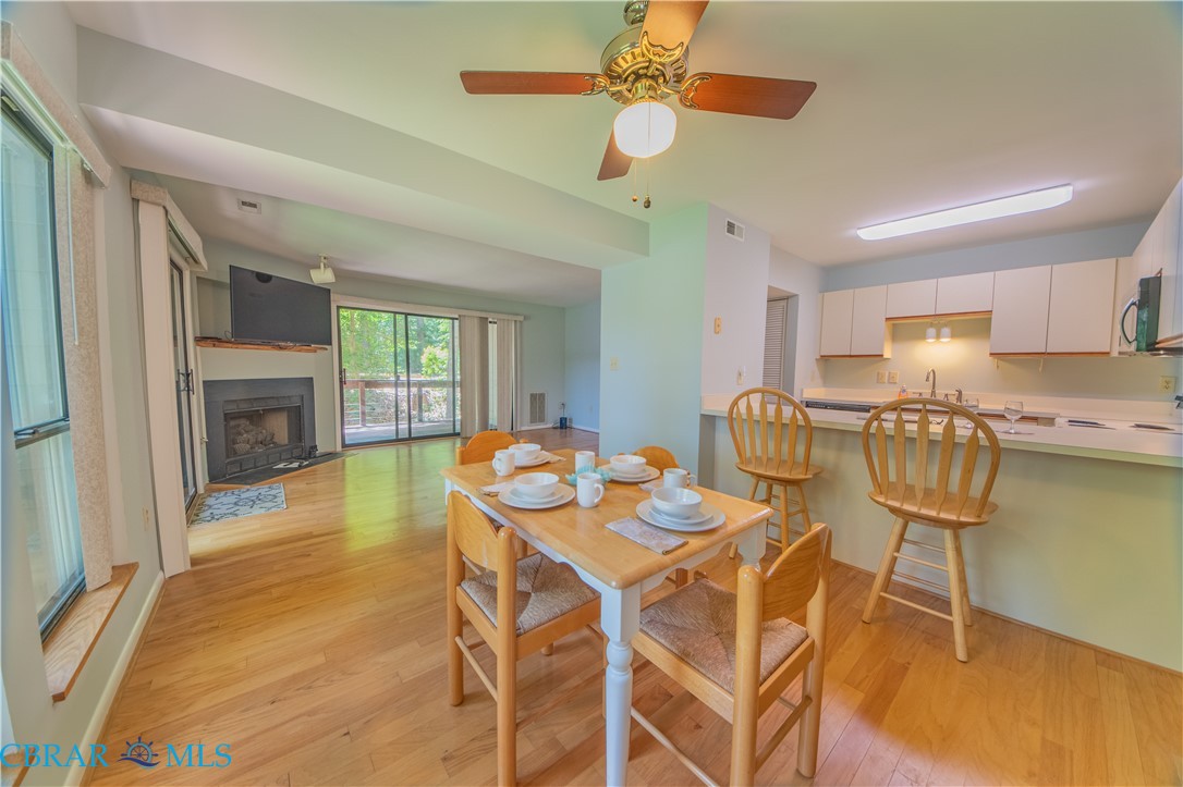 54 Villa Ridge Drive, Unit C Hartfield, VA 23071 - Photo 42 of 45 Dining space with light wood-style flooring, ceiling fan, and a fireplace