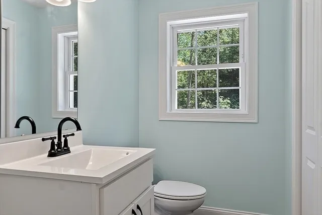 a bathroom with a toilet a sink a mirror and a window