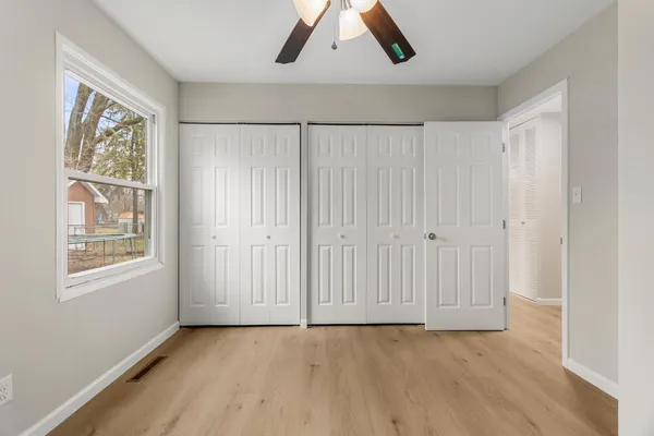 an empty room with wooden floor and windows