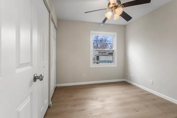 an empty room with windows and fan