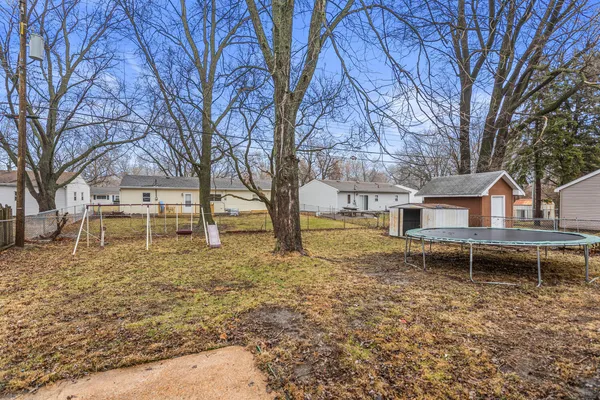 a backyard of a house with wooden fence and large trees