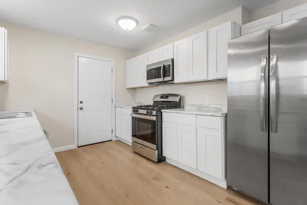a kitchen with cabinets stainless steel appliances and wooden floor