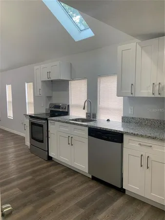 a kitchen with granite countertop white cabinets and appliances