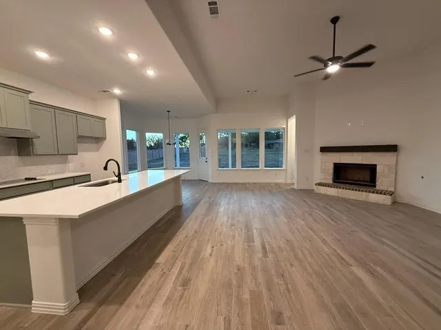 a large white kitchen with wooden floor and a fireplace