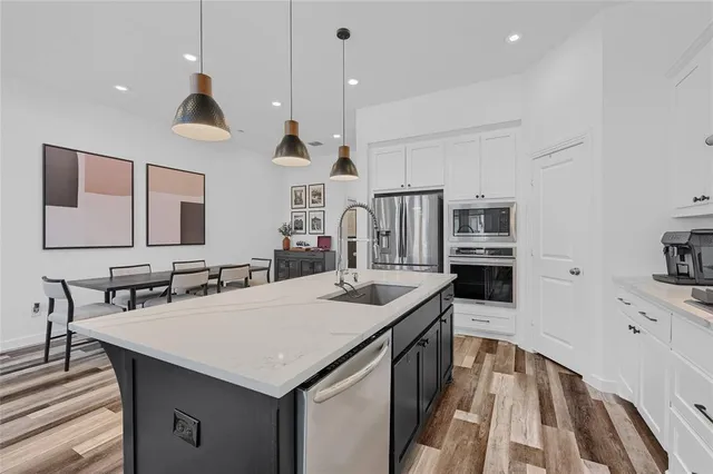 a view of kitchen island with stainless steel appliances sink stove and wooden floor