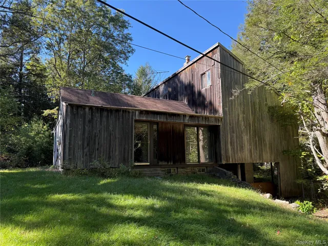 a view of a barn house next to a yard with large trees