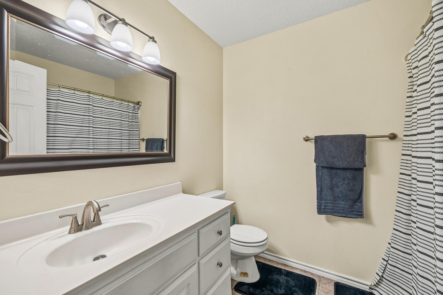 10607 Dover Avenue Lubbock, TX 79424 - Photo 27 of 34 a bathroom with a toilet sink vanity and mirror