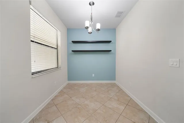 an empty room that has a dining table and a chandelier