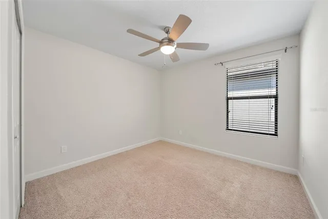 an empty room with a window and a fan