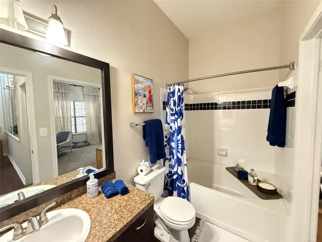 a bathroom with a granite countertop sink mirror vanity and toilet