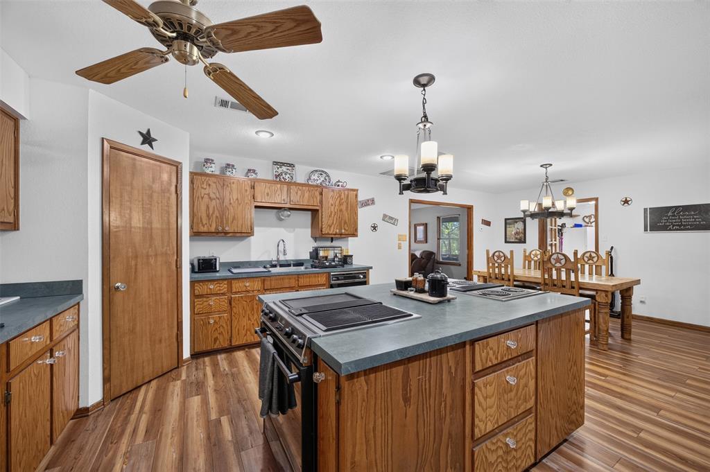 10964 River Ranch Road Kemp, TX 75143 - Photo 17 of 40 Chef's kitchen featuring wood cabinetry, a large center island with slate countertops and built-in cooktop, stainless steel appliances, and hardwood flooring throughout