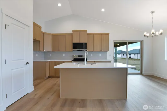 a kitchen with kitchen island a sink a stove a refrigerator cabinets and a wooden floor