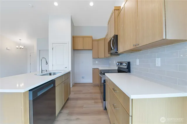 a kitchen with a sink dishwasher a stove and a refrigerator with wooden floor