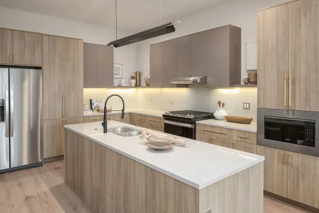 a kitchen with stainless steel appliances a sink a stove a refrigerator and cabinets