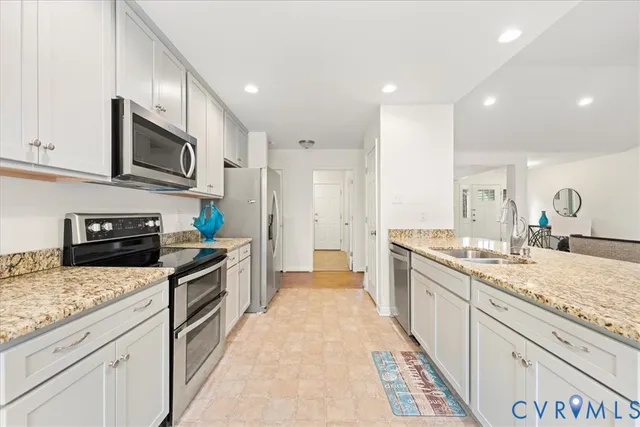 a large kitchen with stainless steel appliances granite countertop a lot of counter space that has a sink and cabinets