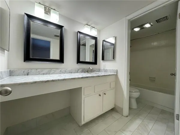 a bathroom with a granite countertop sink mirror and toilet