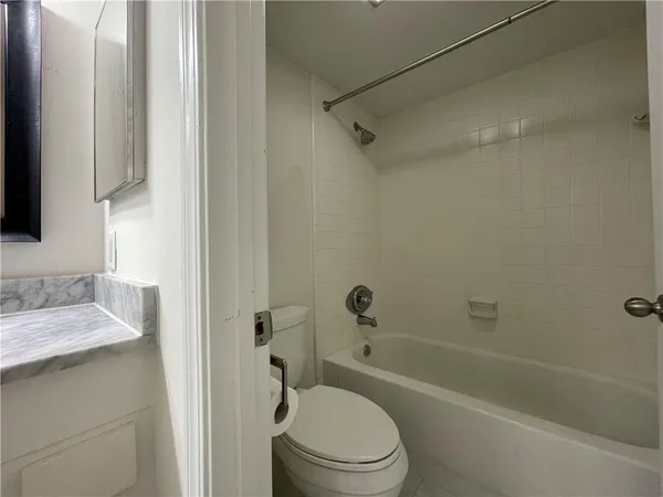 a bathroom with a granite countertop bathtub shower sink vanity and toilet