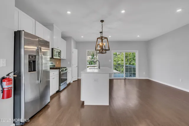 a kitchen with stainless steel appliances granite countertop a refrigerator a stove top oven a sink and a large window