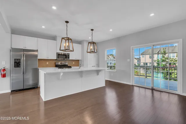 a kitchen with stainless steel appliances granite countertop a sink dishwasher a refrigerator and a stove with wooden floor