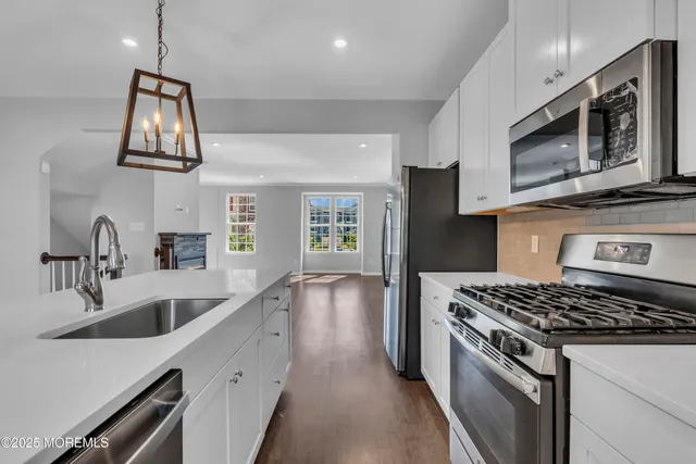 a kitchen with stainless steel appliances granite countertop a refrigerator a stove and a wooden floors