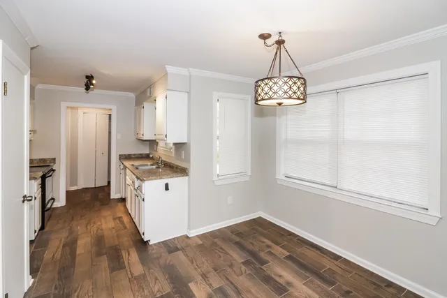 a kitchen with wooden floor a chandelier and a window