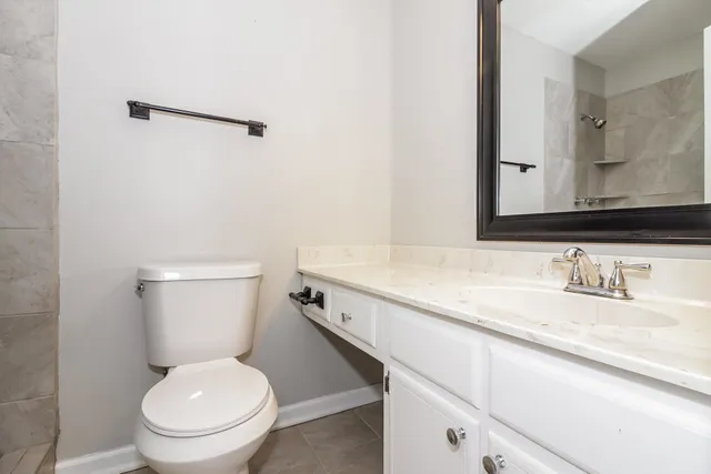 a bathroom with a granite countertop toilet sink and mirror