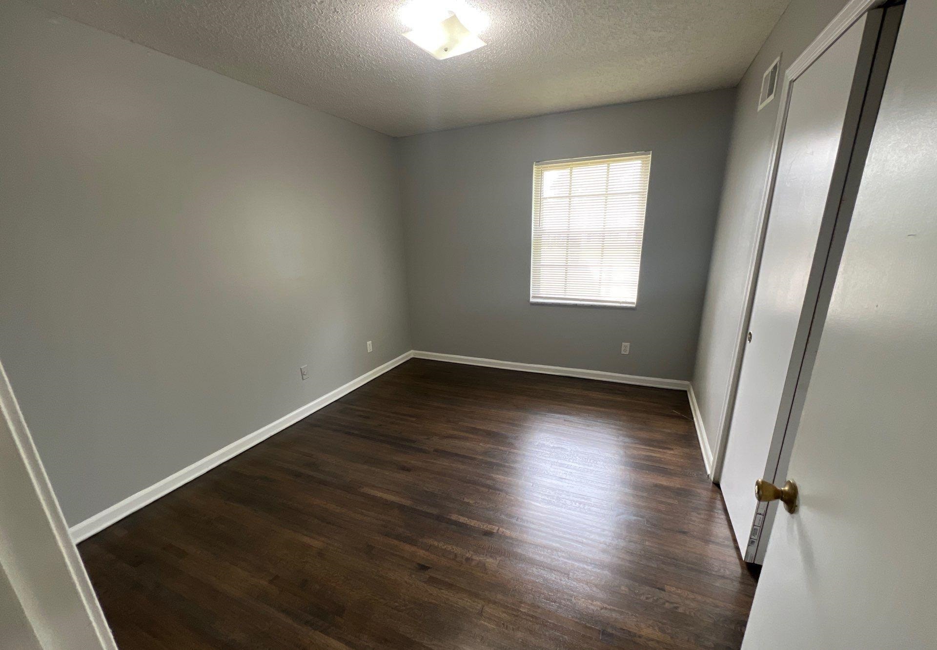 4936 Warrington Road Memphis, TN 38118 - Photo 10 of 13 an empty room with wooden floor and windows
