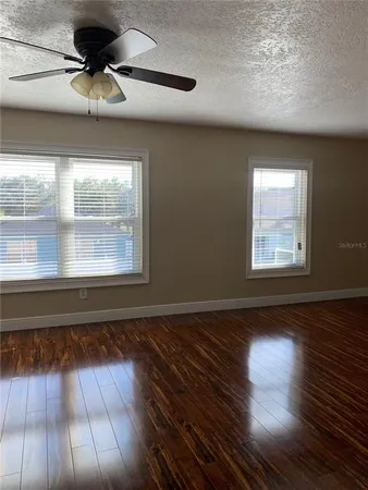 a view of empty room with wooden floor and fan