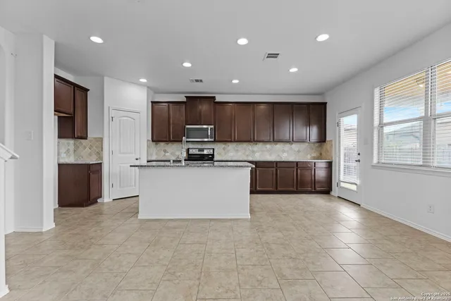 a large kitchen with stainless steel appliances granite countertop a stove a sink a refrigerator and a cabinets