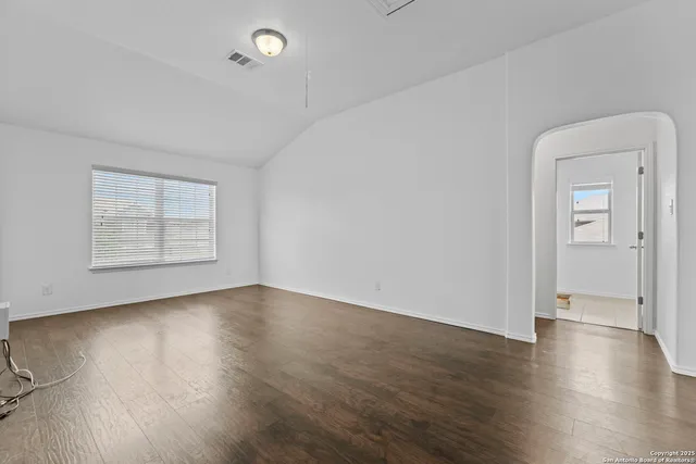 an empty room with wooden floor and windows