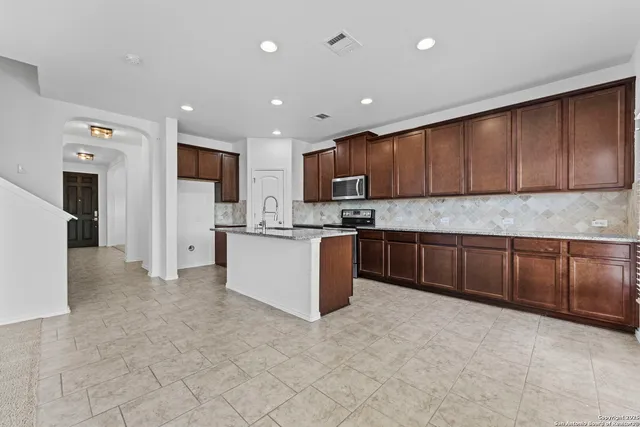 a kitchen with stainless steel appliances granite countertop a stove refrigerator sink and cabinets