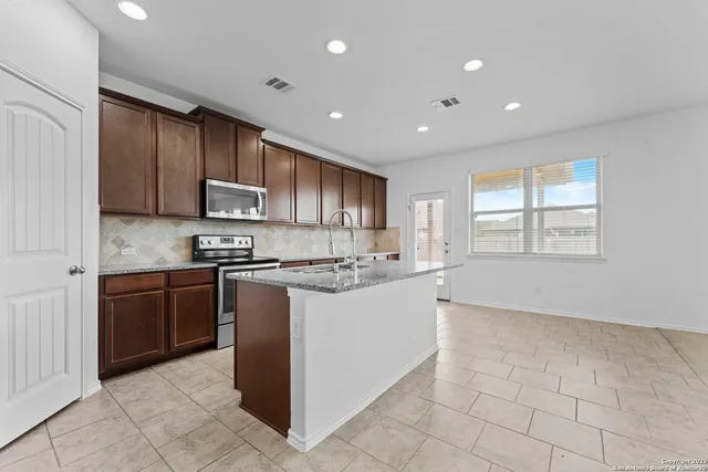 a large kitchen with stainless steel appliances granite countertop a stove a sink and a refrigerator