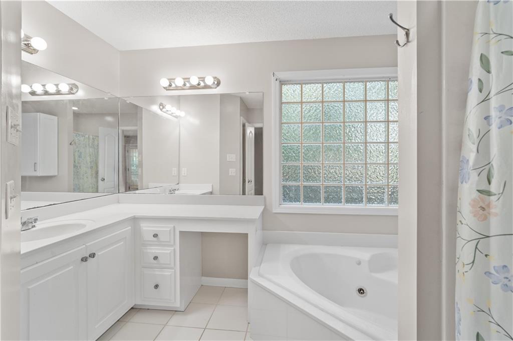 137 Hunters Trail Calhoun, GA 30701 - Photo 15 of 33 a spacious bathroom with a granite countertop sink mirror and a bathtub