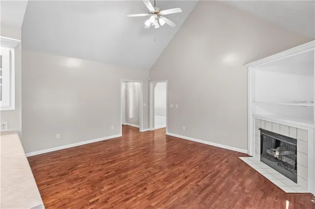 a view of an empty room with wooden floor fireplace and a window