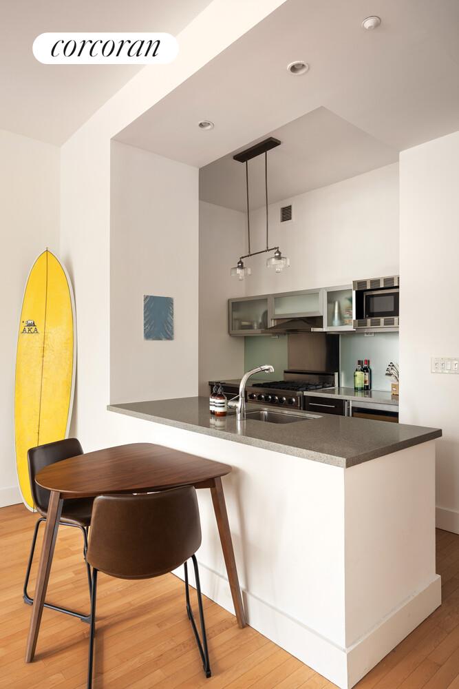 25 West Houston Street, Unit 5B Manhattan, NY 10012 - Photo 4 of 8 a kitchen with stainless steel appliances granite countertop a sink a stove a refrigerator cabinets and a dining table