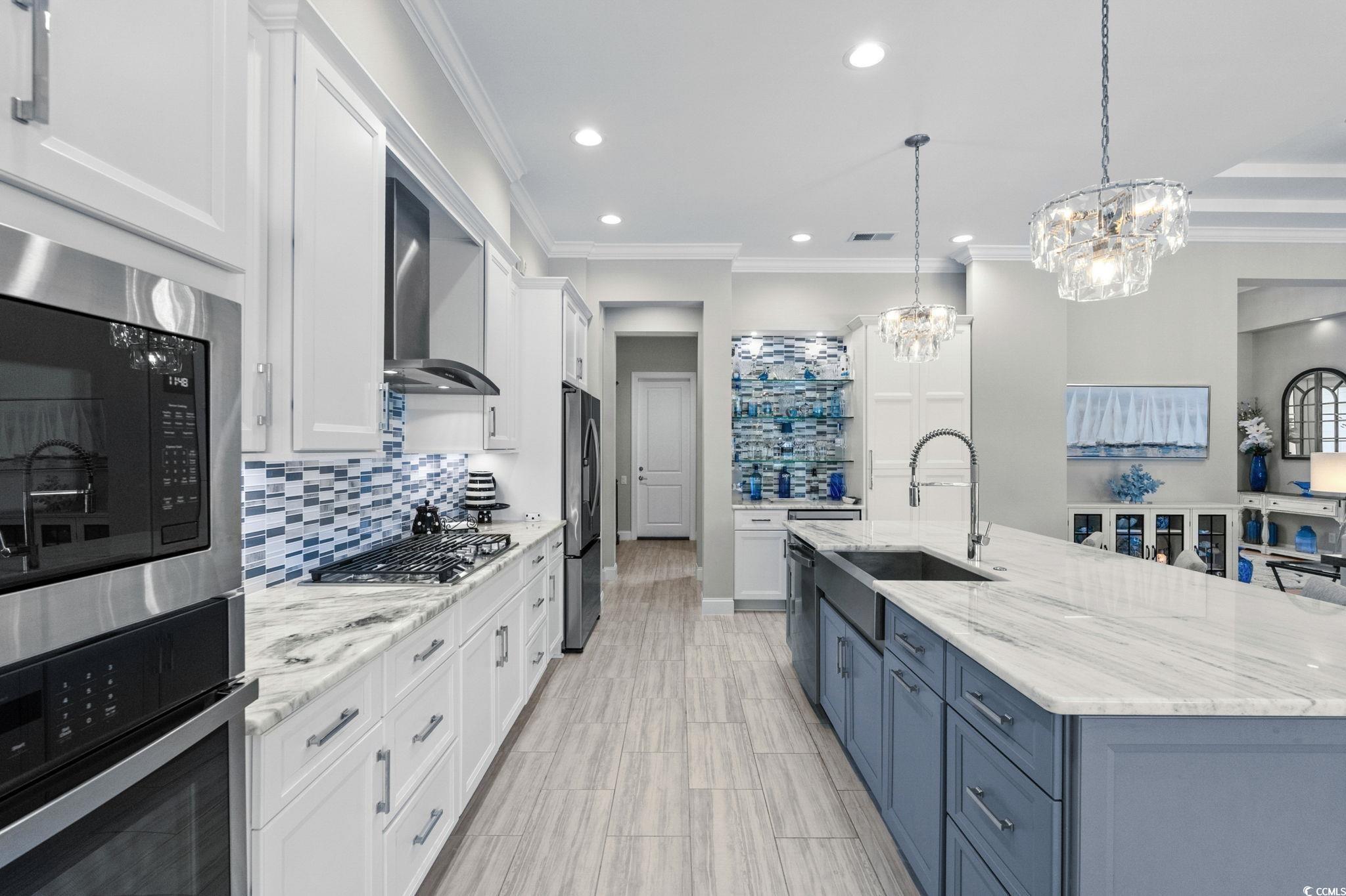 2225 Macerata Loop Myrtle Beach, SC 29579 - Photo 12 of 40 Kitchen with white cabinetry, appliances with stainless steel finishes, light stone countertops, crown molding, and decorative light fixtures