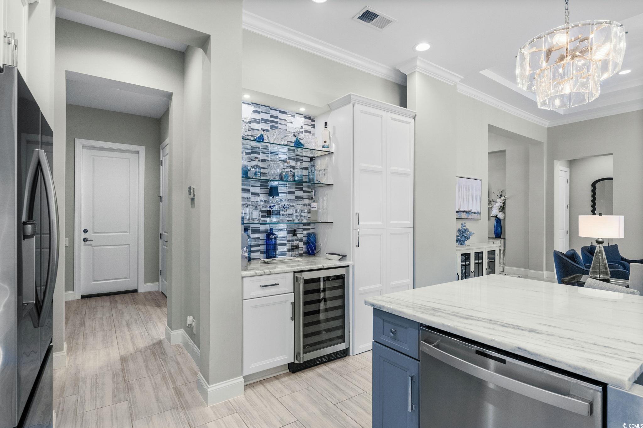 2225 Macerata Loop Myrtle Beach, SC 29579 - Photo 13 of 40 Indoor bar featuring white cabinetry, light stone countertops, stainless steel appliances, crown molding, and wine cooler