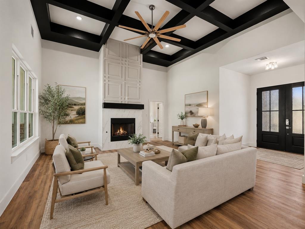 328 Slimp Bluff Azle, TX 76020 - Photo 6 of 30 Spacious living area featuring a coffered ceiling with a wood-blade fan, a fireplace with a marble-finish surround, and a decorative paneled accent wall