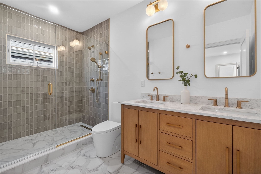 202 Powder House Boulevard, Unit 1 Somerville, MA 02144 - Photo 14 of 26 a bathroom with a granite countertop sink toilet and shower