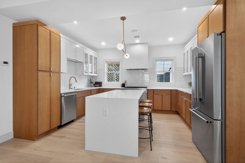 202 Powder House Boulevard, Unit 1 Somerville, MA 02144 - Photo 4 of 26 a kitchen with stainless steel appliances granite countertop a refrigerator a oven a sink and white cabinets with wooden floors