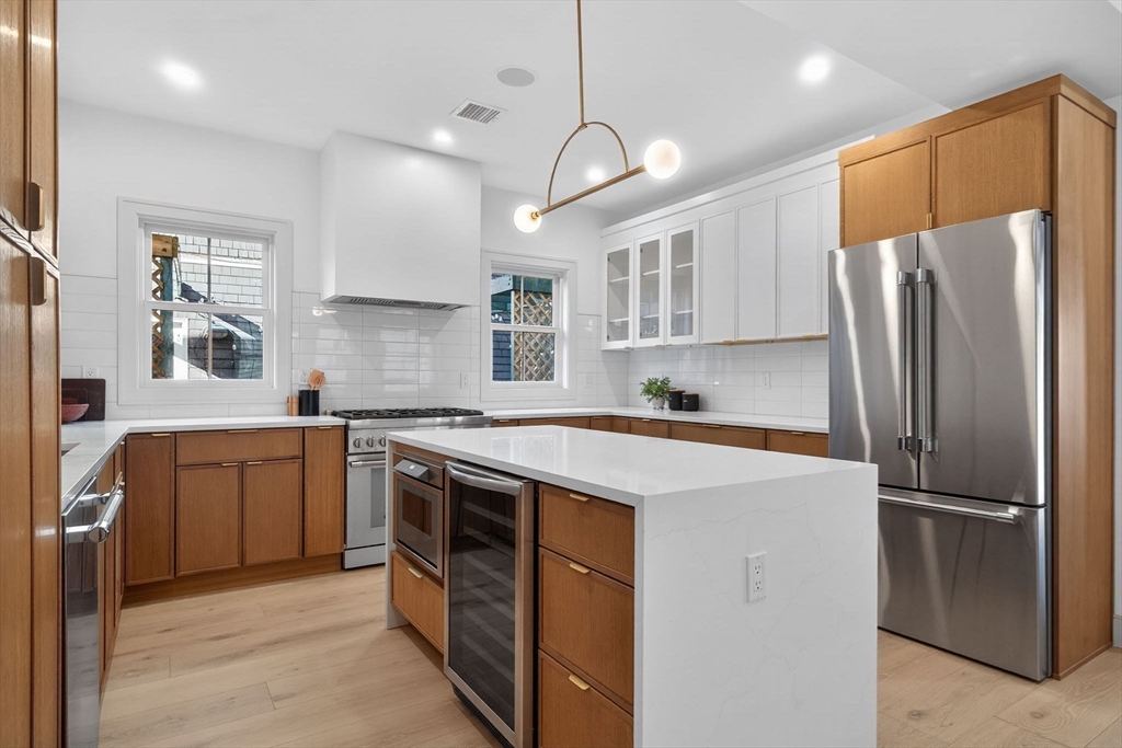 202 Powder House Boulevard, Unit 1 Somerville, MA 02144 - Photo 5 of 26 a kitchen with stainless steel appliances granite countertop a refrigerator a sink dishwasher a stove with white cabinets and wooden floor